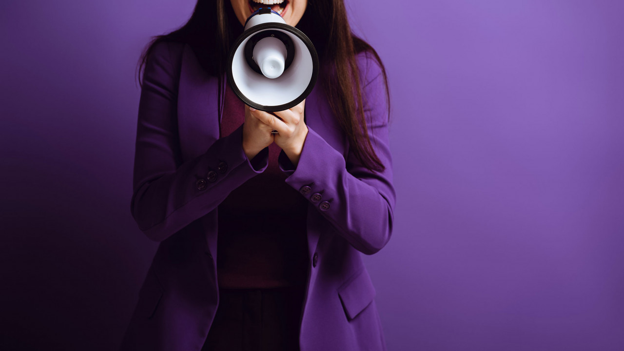 kobieta ogłaszająca informacje przez megafon, ilustracja do artykułu tłumaczącego skrótowiec TBA