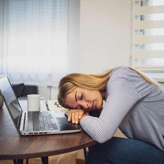 Kobieta drzemiąca przed komputerem w pracy