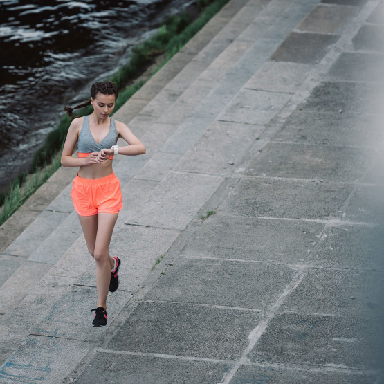 Biegnąca kobieta sprawdza swoje tempo, ilustracja do kalkulatora online przeliczającego tempo na prędkość