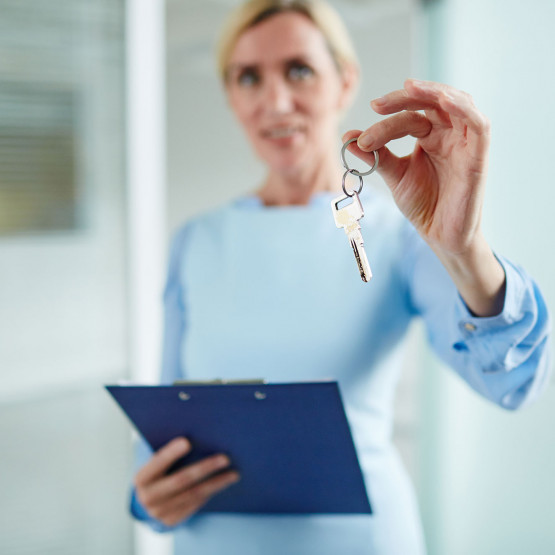 Pośredniczka wręczająca klucz do mieszkania, ilustracja do artykułu o stronach internetowych z mieszkaniami w Holandii